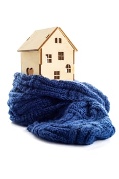 Wooden toy house is wrapped in a warm scarf isolated on white background. House insulation concept. Warm house concept