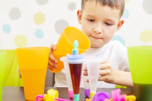 Child making ice cream from fruit juice on table at home.