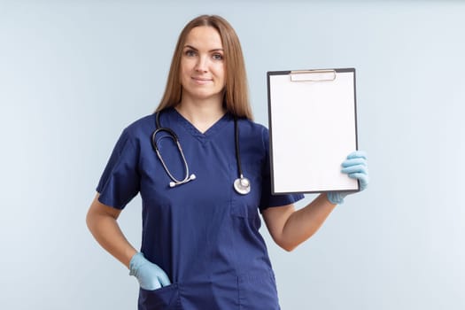 Female nurse or doctor holding a clipboard with blank white paper on a blue background. Doctor holding a clipboard