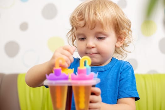 Child making ice cream from fruit juice on table at home.