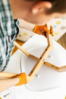 Self-assembly furniture concept. The young man himself assembling chairs. He uses tools for furniture
