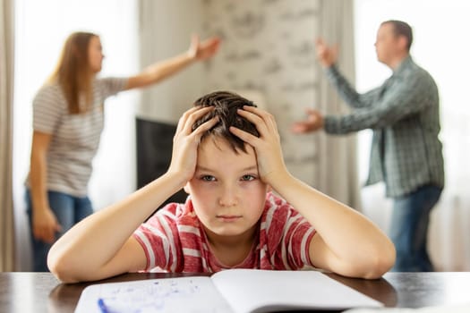 A son feels frustrated while his parents fight in the background. Family conflicts or divorce impact on on child development