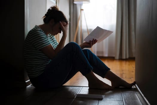 Silhouette of a sad woman sitting on the floor of her apartment. Getting bad news, eviction, depression, trouble , death in the family