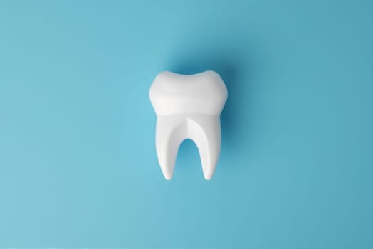 White healthy tooth model on blue background with copy space. Dental care and healthcare concept. Oral care, restoration of teeth