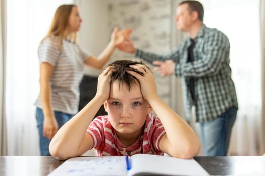 A son feels frustrated while his parents fight in the background. Family conflicts or divorce impact on on child development