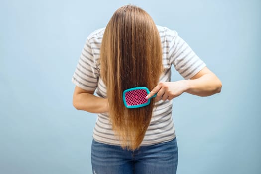 Young beautiful brunette woman brushing her long healthy hair. Haircare concept.