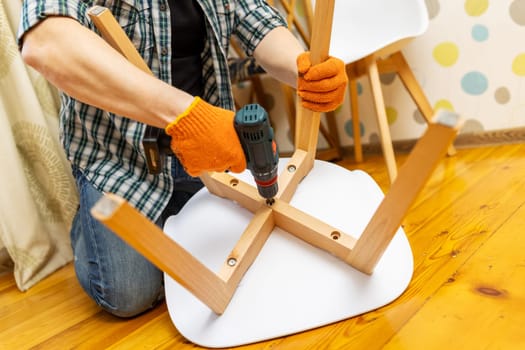 Assemble the furniture. A man assembling a chair. Furniture assembler with a drill. Craftsman with tools to repair a chair