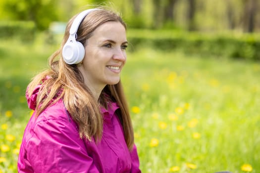 Beautiful young woman likes to listen to music with headphones, feeling happy and relaxed in the park