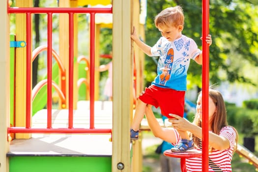 Cute little kid boy having fun while playing on the playground in the daytime in summer. Outdoor activity. Outside education.