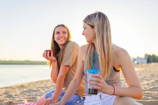 Two young beautiful women are having fun on beach and smiling. Have a carefree time with friends