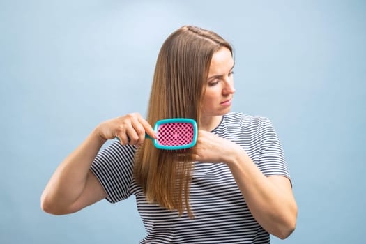 Young beautiful brunette woman brushing her long healthy hair. Haircare concept.