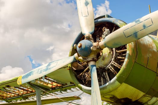 A fragment of an airplane wing with a four-bladed aircraft propeller against blue sky