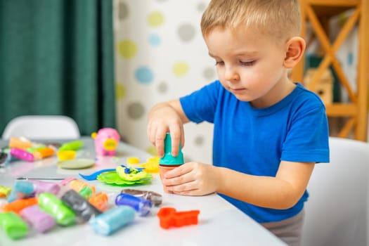 Kids playing with play dough. Cute children sitting at the table and plays with playdough. Creative leisure activity concept