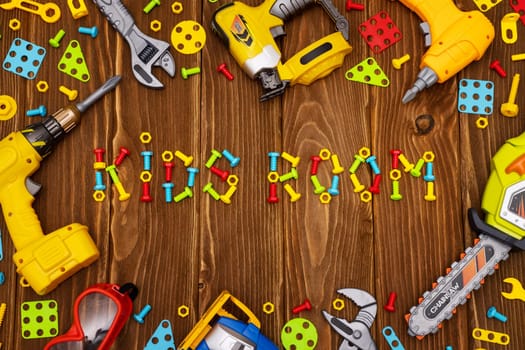 Colorful toy tools, bolts and nuts as frame with text Kids Room on wooden background. Top view. Flat lay
