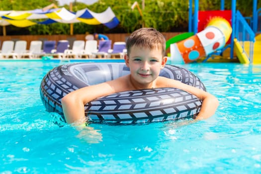 Boy swim on inflatable ring in swimming pool outdoors.