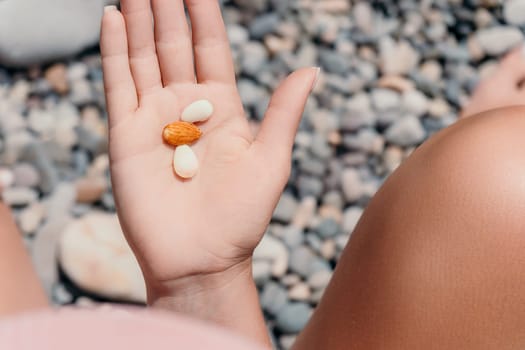 Woman eating milky almond nuts. A young caucasian woman choping fresh green almond after morning fitness yoga near sea. Only hands are visibly. Healthy vegan food. Slow motion. Close up