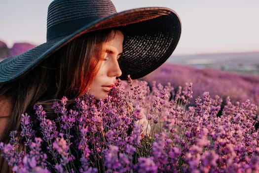 Close up portrait of young beautiful woman in a white dress and a hat is walking in the lavender field and smelling lavender bouquet.