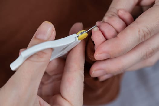 Mom cuts her newborn son's fingernails with small children's scissors