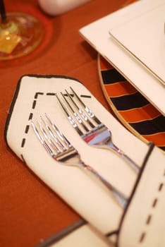 Two forks displayed on a wooden table with a napkin underneath.