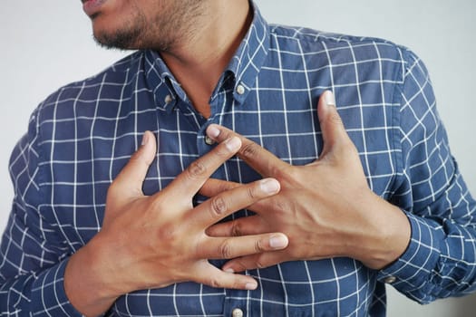 young man suffering pain in heart and holding chest with hand .
