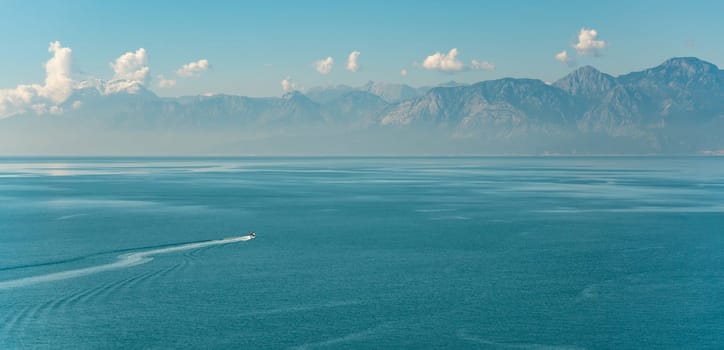 Antalya landscape with a boat sailing on the sea and mountains in the background