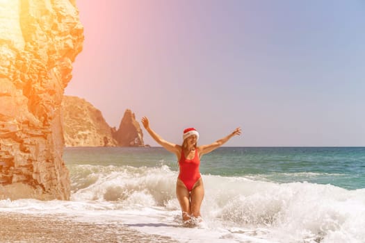 A woman in Santa hat on the seashore, dressed in a red swimsuit. New Year's celebration in a hot country