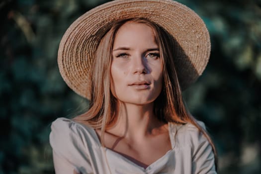 Woman with straw hat stands in front of vineyard. She is wearing a light dress and posing for a photo. Travel concept to different countries.