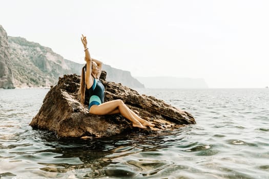 Woman beach vacation photo. A happy tourist in a blue bikini enjoying the scenic view of the sea and volcanic mountains while taking pictures to capture the memories of her travel adventure