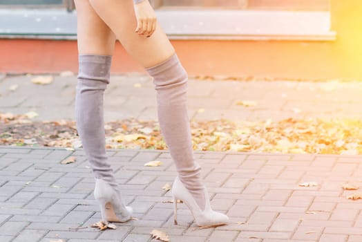 Fashion image of perfect long slim woman legs in an autumn park.