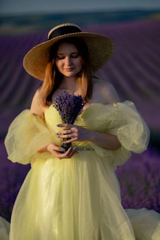 Lavender sunset girl. A laughing girl in a blue dress with flowing hair in a hat walks through a lilac field, holds a bouquet of lavender in her hands