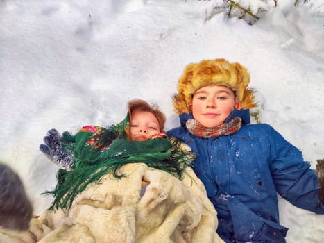 Two cute happy little cheerful children having fun in winter snow forest. Photo shoot in stylized clothes of the USSR. Fur Hat with earflaps