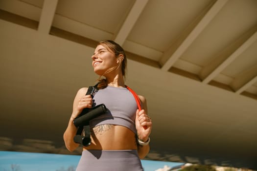 Beautiful athletic woman with a resistance band slung around her neck standing outdoors