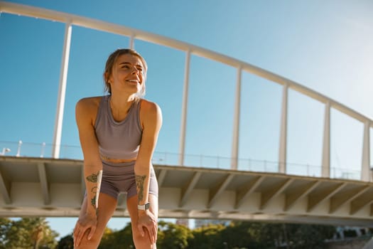 Smiling woman in sportswear have a rest after workout outside standing on building background