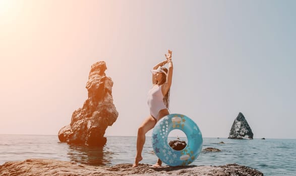 Woman summer sea. Happy woman swimming with inflatable donut on the beach in summer sunny day, surrounded by volcanic mountains. Summer vacation concept