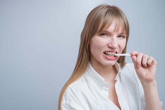 Young woman with metal braces on her teeth is chewing gum. Copy space