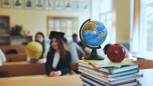 Globe of the world with textbooks and an apple in the background of a lesson in a school classroom