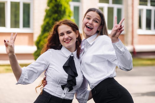 Portrait of two high school girls against the backdrop of the school