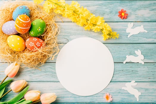 Happy Easter Day Concept. Flat lay of holiday banner background web design easter eggs in brown nest and blank paper circle on blue wooden background with empty copy space, celebration greeting card