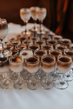 Catering. Drinks on wedding party. Cocktail glasses full of red alcohol stand on table. Beautiful row line of different colored alcohol cocktails with mint on a open air party, martini, vodka fresh