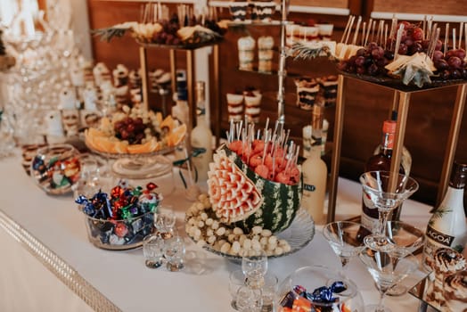 stylish desserts with strawberry, candy bar with sweets at luxury wedding reception. catering at restaurant. cupcakes macaroons on table. space for text. cakes, strawberry tartlet, cupcakes macarons