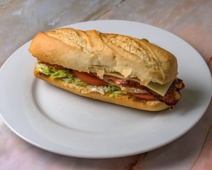 delicious,typical spanish bacon and cheese sandwich with lettuce and tomato .