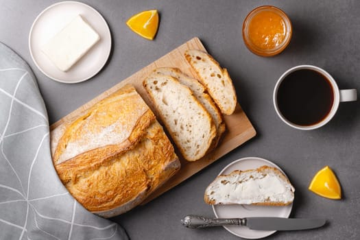 Cup of coffee, sandwich with orange jam, loaf of bread on the grey background. Breakfast concept.