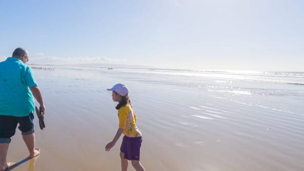 Father and daughter enjoy a leisurely winter walk along the picturesque Pismo Beach, sharing quality time together amid the serene backdrop of gently crashing waves.