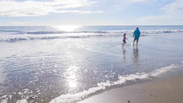 In California, a father and daughter share a serene winter walk along the deserted sands of El Capitan State Beach.