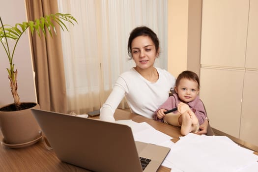 beautiful businesswoman working at home with her little child daughter. Stay at home