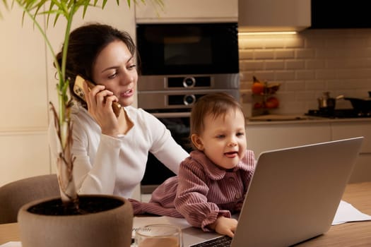 happy businesswoman working at home with her little child girl. woman talking on the phone