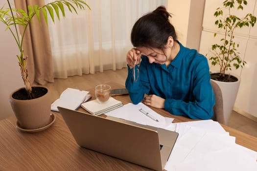 Stressed tired woman working at laptop at home