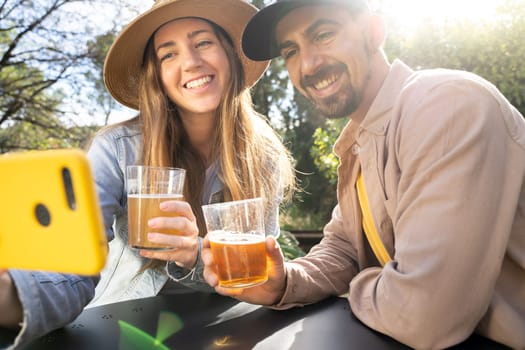 Happy couple friends have drinks and taking selfie photo in a backyard on sunny day toast together. High quality 4k footage