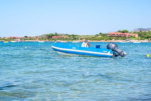 Motor boat in the sea against the coast with houses, mountains in Sardinia, Italy.