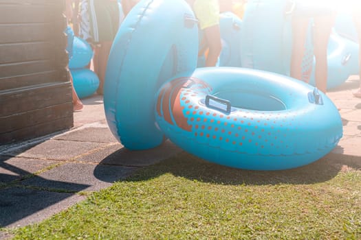 Bright blue inflatable wheels and blurred people background on sunny day.